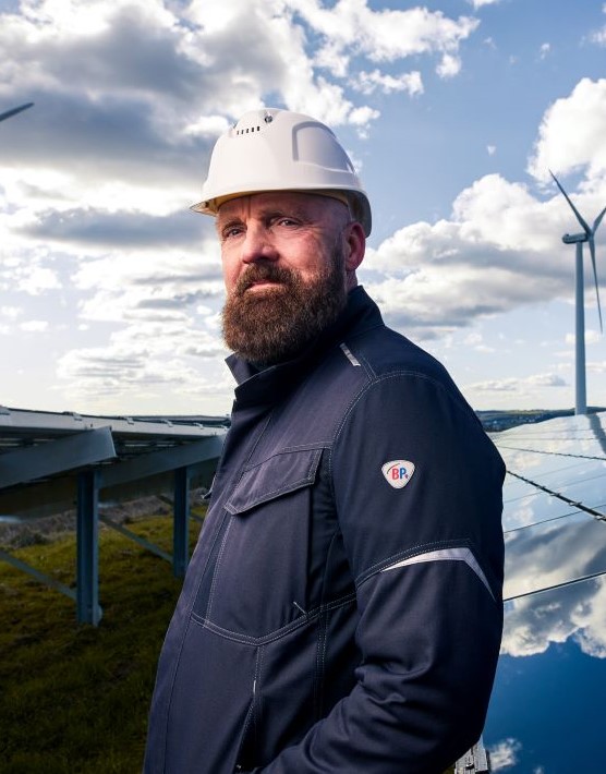 A worker on a photovoltaic system wears protective clothing for electric arcs.